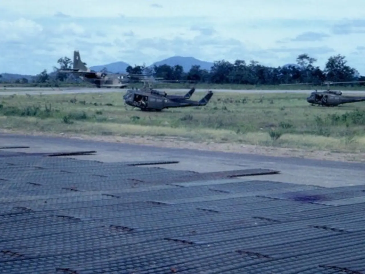 In the image there are three helicopters on the grassland and behind there is an aeroplane on the...