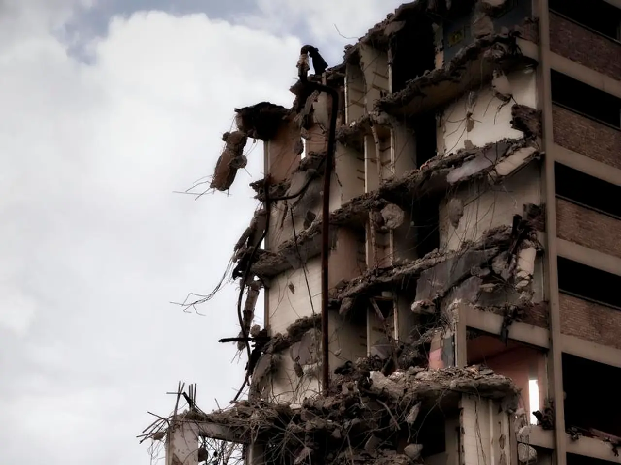 In this picture we can see a collapsed building. In the background of the image we can see the...