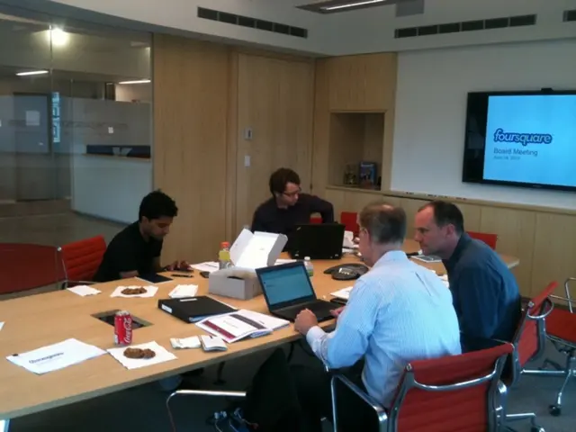 In this image there are group of people, they are sitting on the chairs around the table and there...