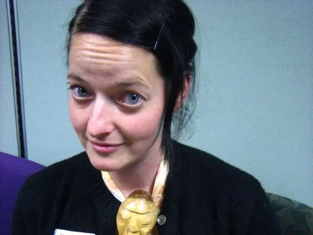 This is the woman sitting on the chair. She wore a black jacket and yellow dress. This looks like a...