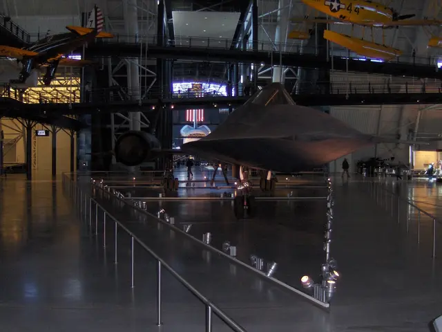 There are aircrafts hanged. There are railings. In the background there are people, rods, pillars...