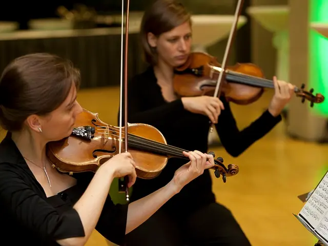 There are two men in the given picture. Both of them are playing a violin in their hands. In front...