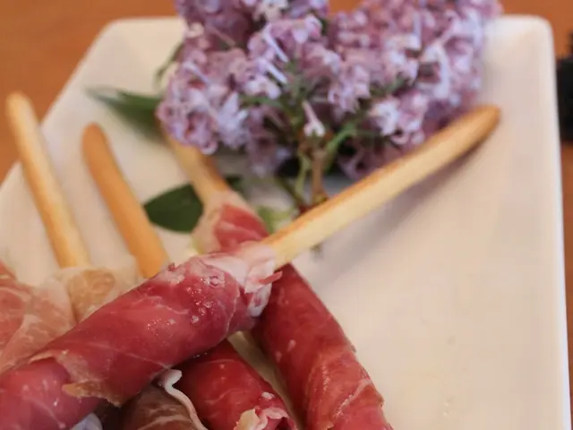 In this image there is a food item with garnish on the plate. In the background there is a table....