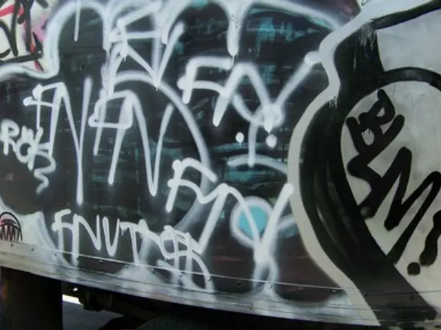 In this picture, we can see a few vehicles, poles, buildings, road and the sky.