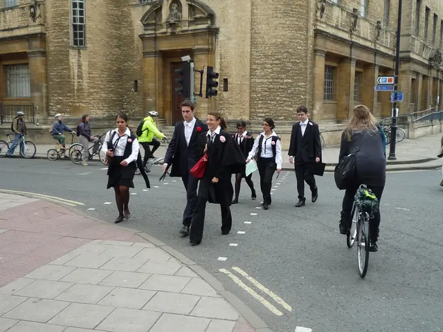 In this image there are group of persons who are crossing the road and riding bicycles and at the...